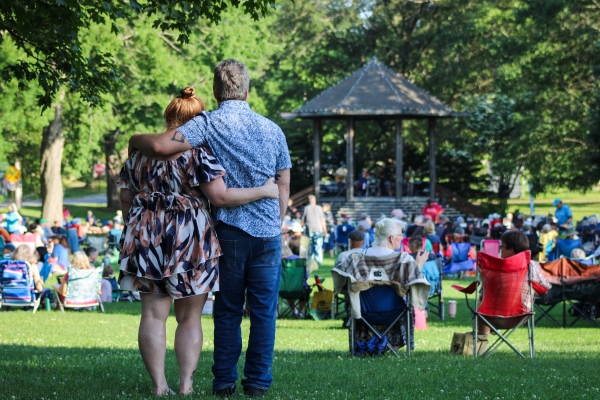 Couple with arms around each other watching music on the mall